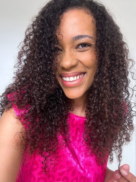 Mulher negra de blusa com cor pink, mostrando o resutado dos cabelos cacheados com o Umidificador Forever Liss Chuva de Crespo 